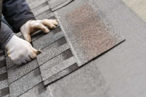 A homeowner in casual clothes inspects their roof for storm damage from a backyard, with missing shingles visible.