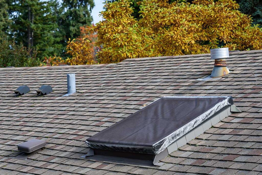 Close-up of metal flashing guiding rainwater around a chimney and roof shingles